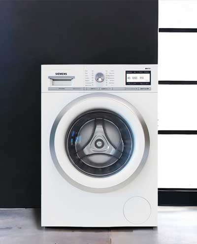 A buit in washing machine with a black and white wall in the background